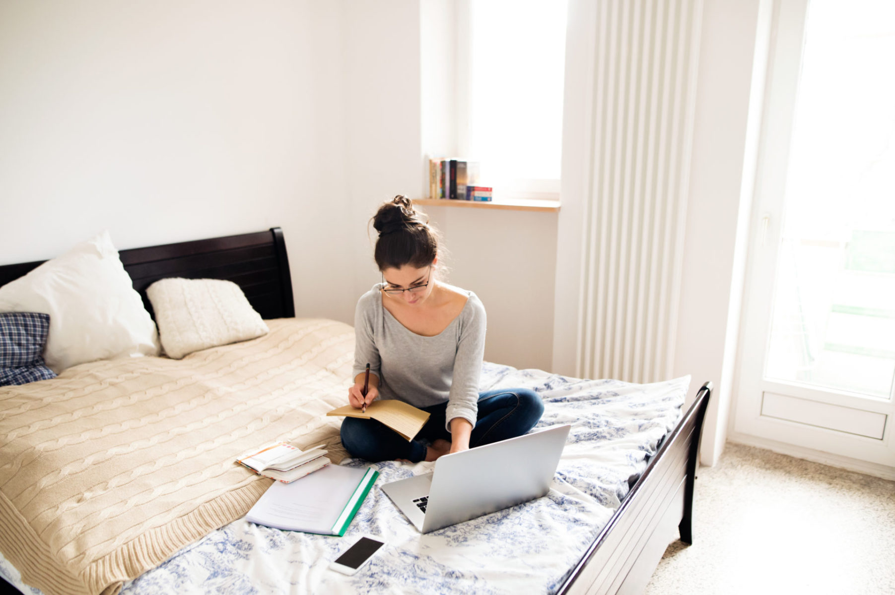 Beautiful young woman sitting on bed, working. Home office. Livre Si simple Bruno Savoyat Télétravail