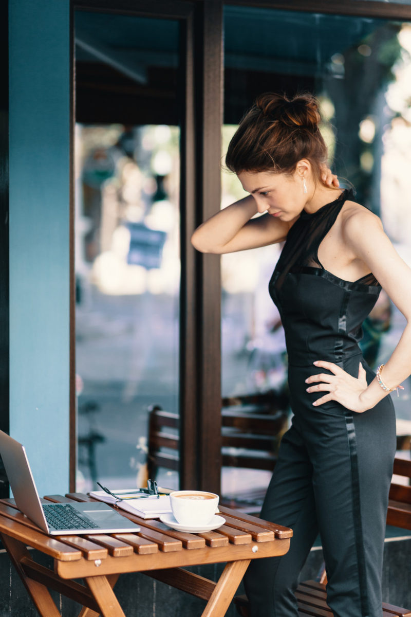 Elegant businesswoman standing near a table in a cafe while look Vidéoconférence, livre "Si simple!" de Bruno Savoyat