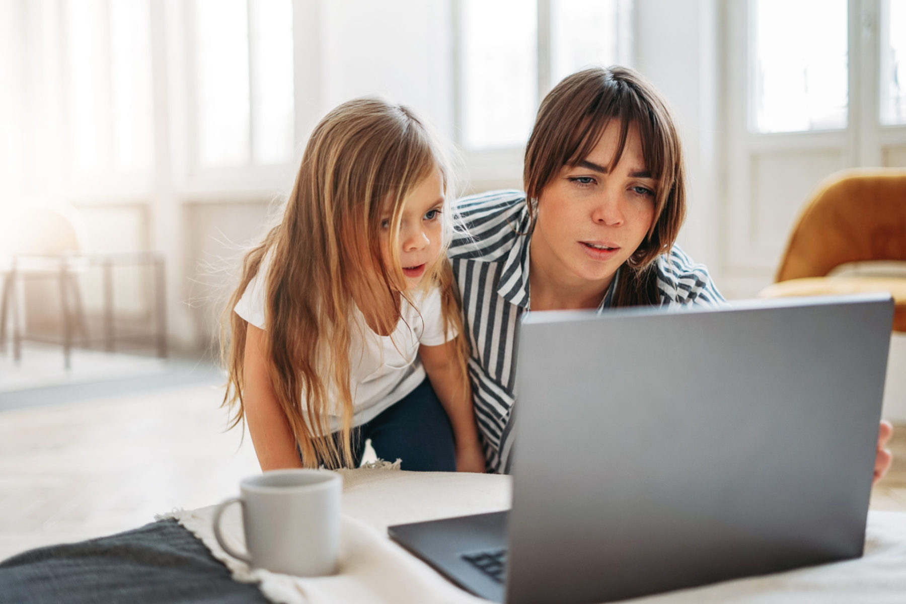 Working mom freelancer with little daughter look to laptop together in bright interior at home Livre Si simple Bruno Savoyat Télétravail